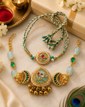Jadau Kundan Gold and green bhaiya bhabhi rakhi set with pearl, elephant, and bell details displayed with roli, diya, flowers, gift box, and peacock feather.