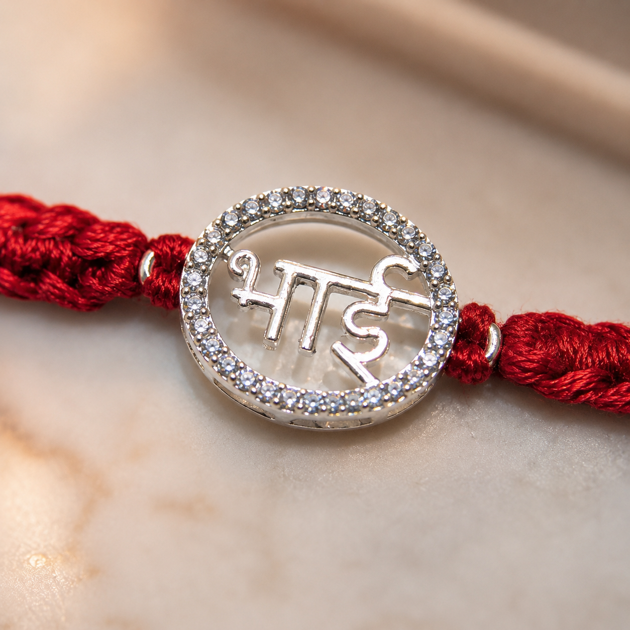 Close up of Bhai rakhi silver pendant with stone border and red braided thread detail