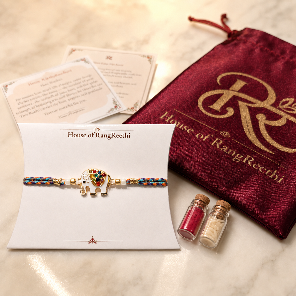 Multicolor braided elephant rakhi displayed on a House of RangReethi card with red potli, roli chawal bottles, and Raksha Bandhan greeting cards.