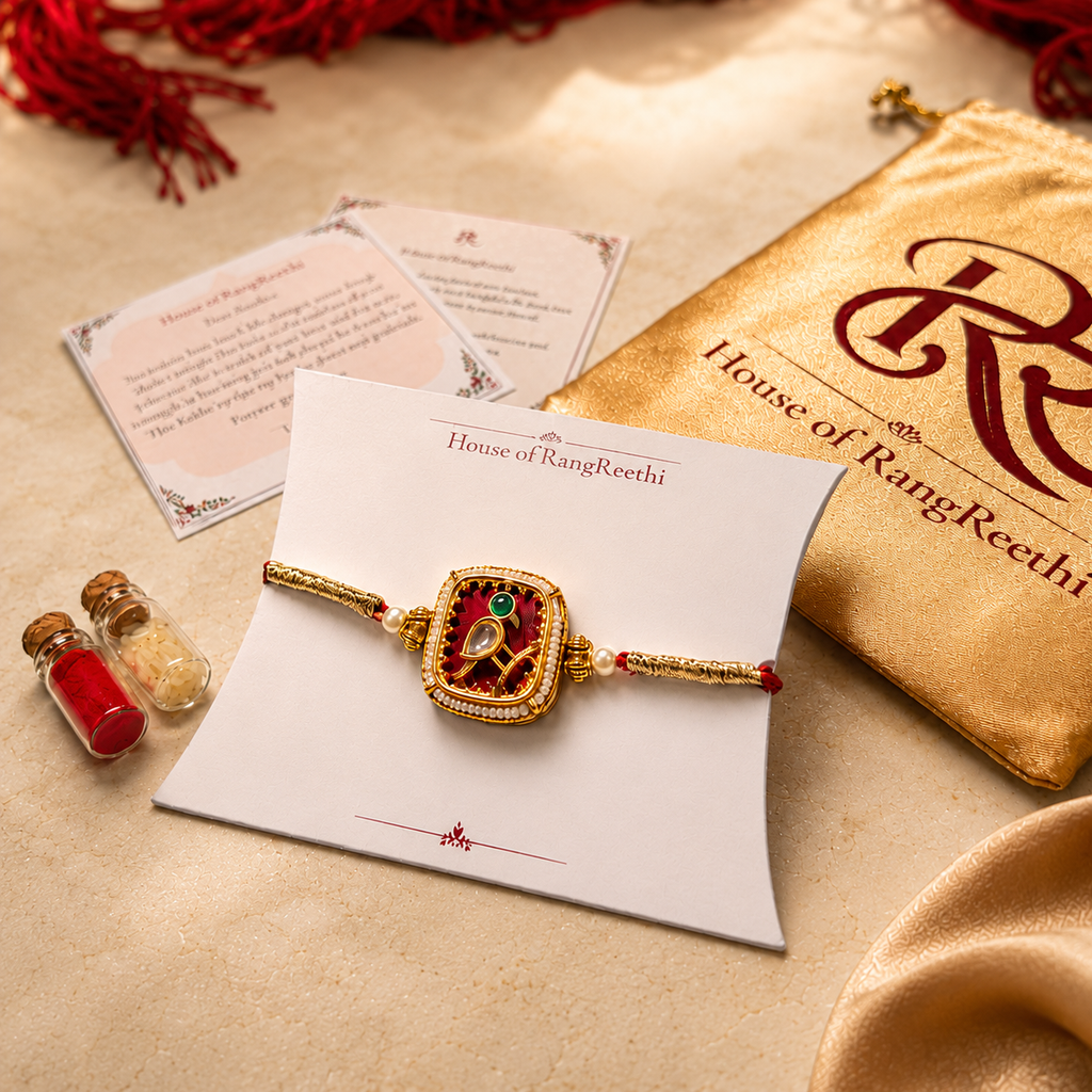 Red Jadau Kudan rakhi displayed on a House of RangReethi card with gold potli, roli chawal bottles, and Raksha Bandhan greeting cards.